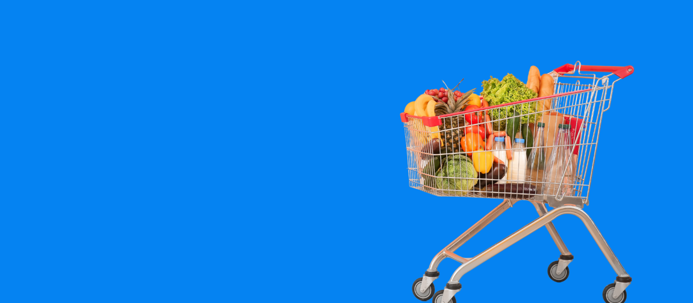 Metal grocery cart filled with assorted groceries and fresh produce.