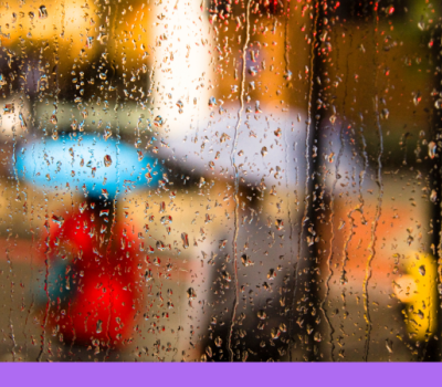 Rain falling on a window with people holding umbrellas blurred through the window.  Rain falling on a window with people holding umbrellas blurred through the window.